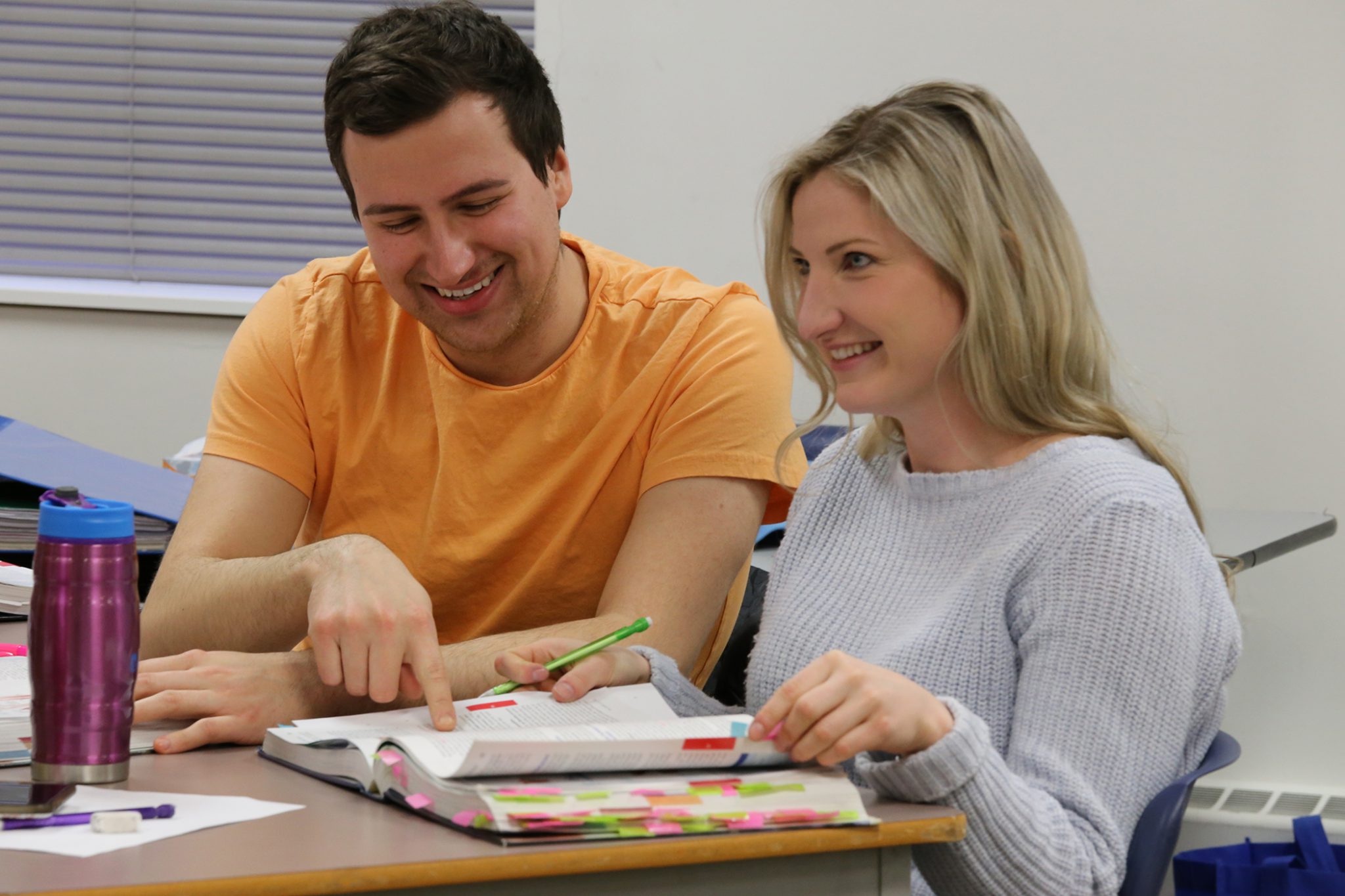 People studying a textbook at aurora college.